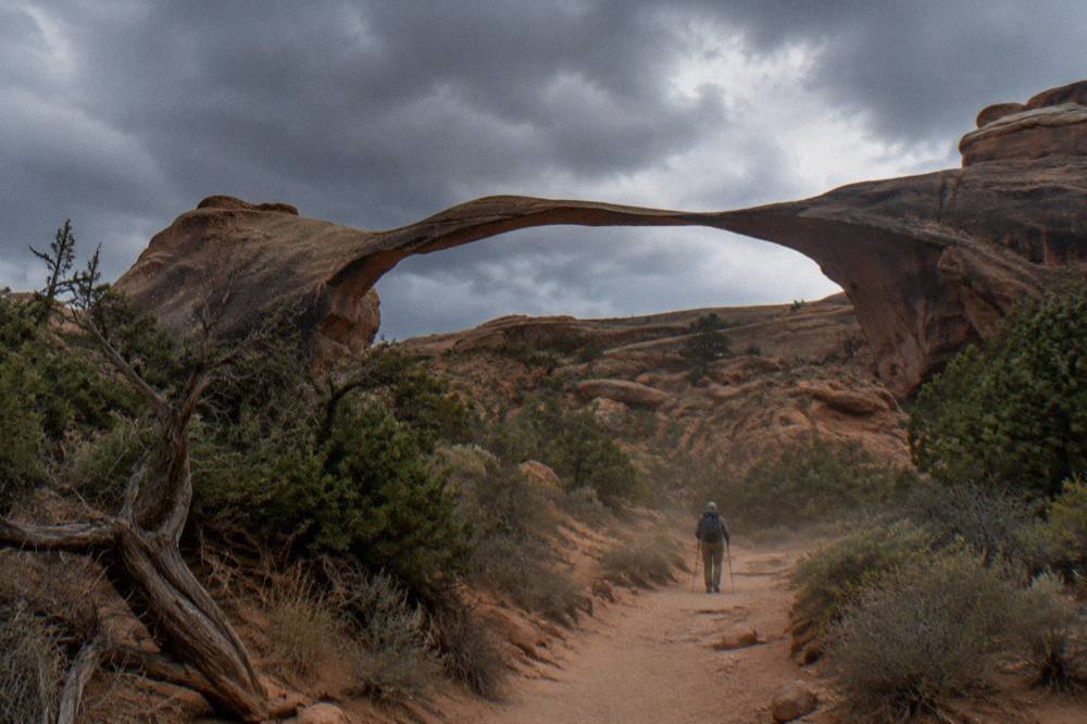 A long thin span of sandstone stretching between two rock fins under a clear sky