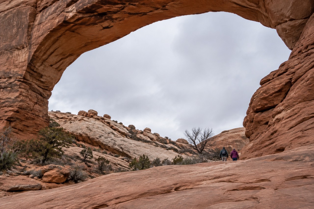 A wide sandstone arch standing against an open desert sky at Arches National Park