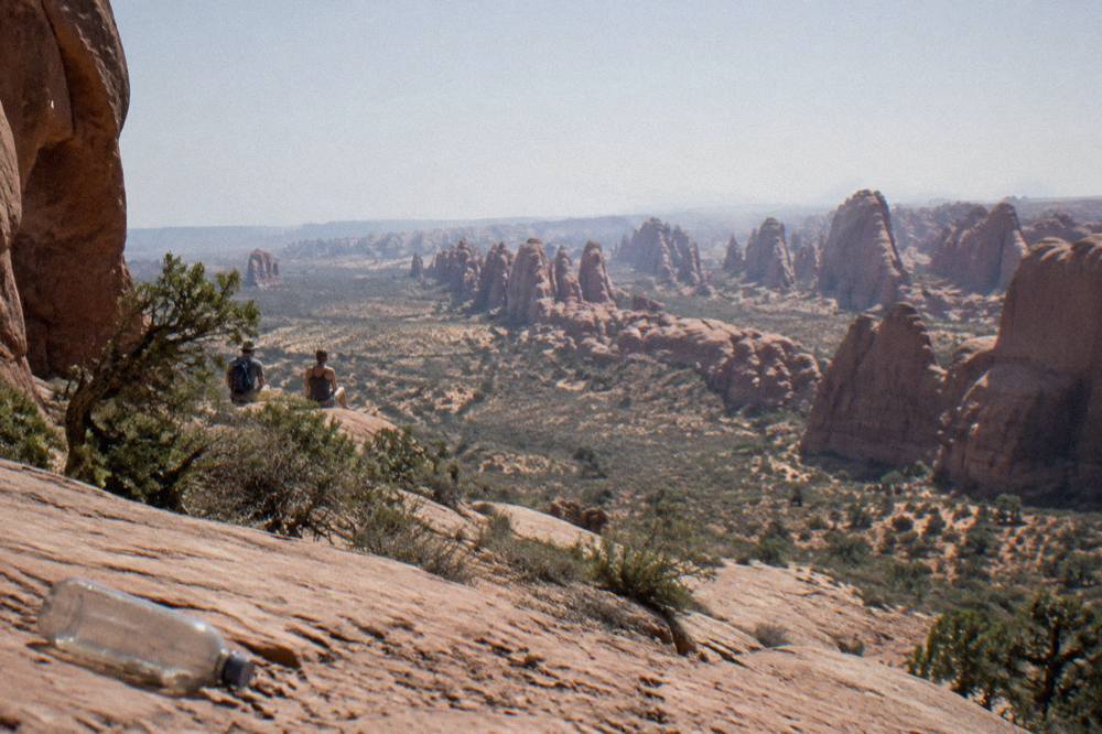 Sandstone arches and rock fins seen across an open desert plain under a wide sky.