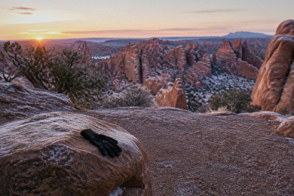 Soft pink morning light on sandstone fins and rock formations seen from an empty overlook