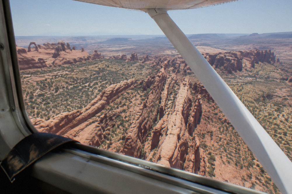 An aerial view of narrow red sandstone ridges and canyons stretching to a distant horizon under hazy sky
