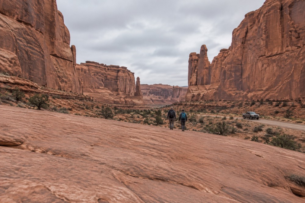 A four-wheel-drive trail crossing slickrock benches between tall red rock walls