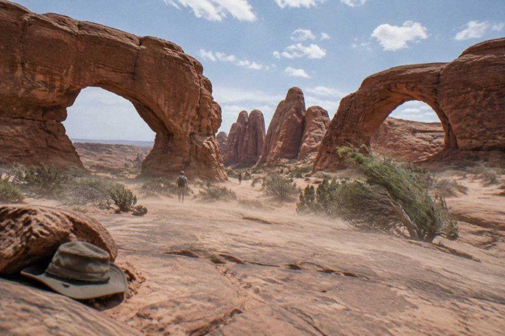 Two large sandstone arch openings facing each other across a desert terrace with rock fins behind