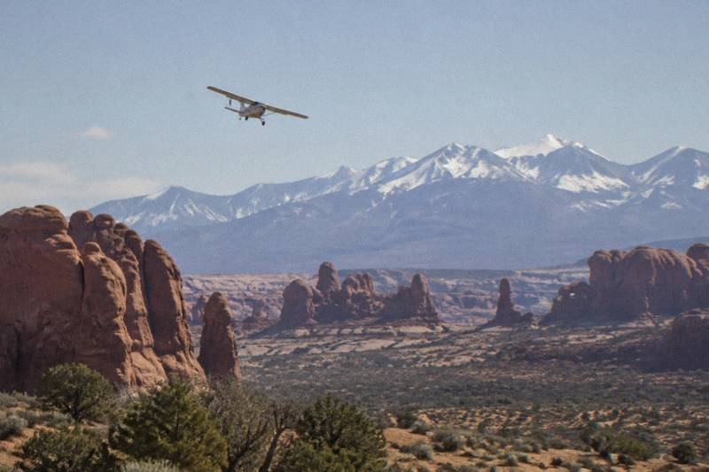 Small airplane wing above sandstone arches, deep canyons and the Colorado River near Arches National Park