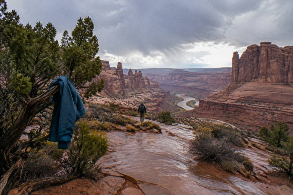 A wide desert overlook with layered canyon walls dropping to a river bend below