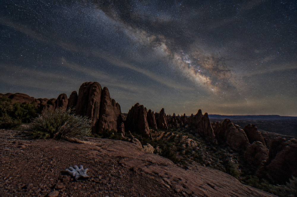 The Milky Way band stretching over dark sandstone fins under a starry sky