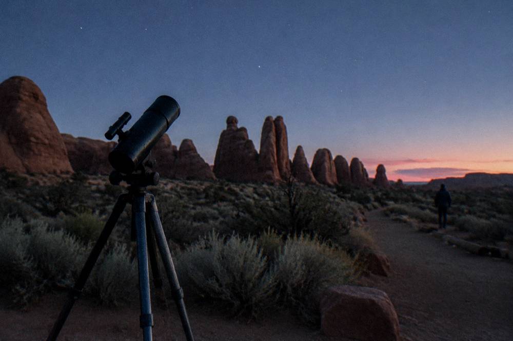 Telescope silhouette and open desert horizon under a dense star field