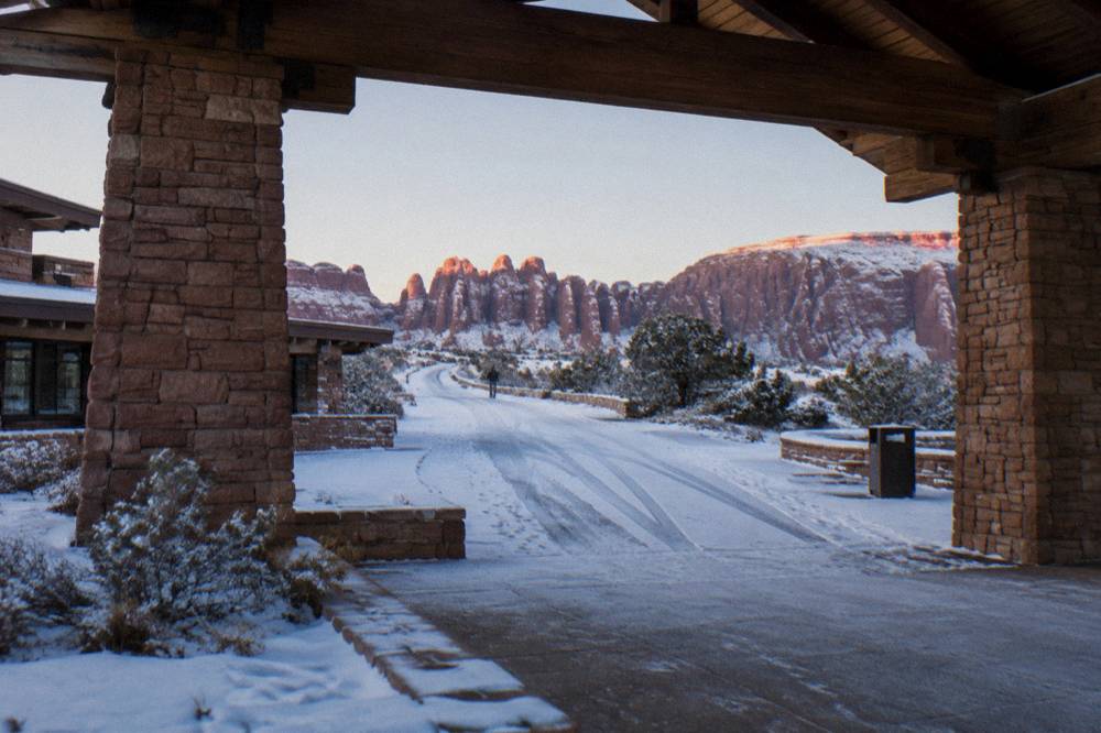 Park entrance sign with snow dusted red rock in winter light