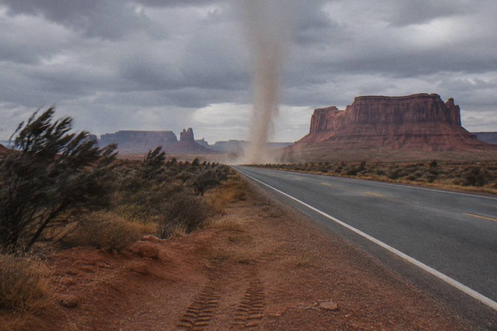 Empty desert highway stretching toward red rock mesas in the distance