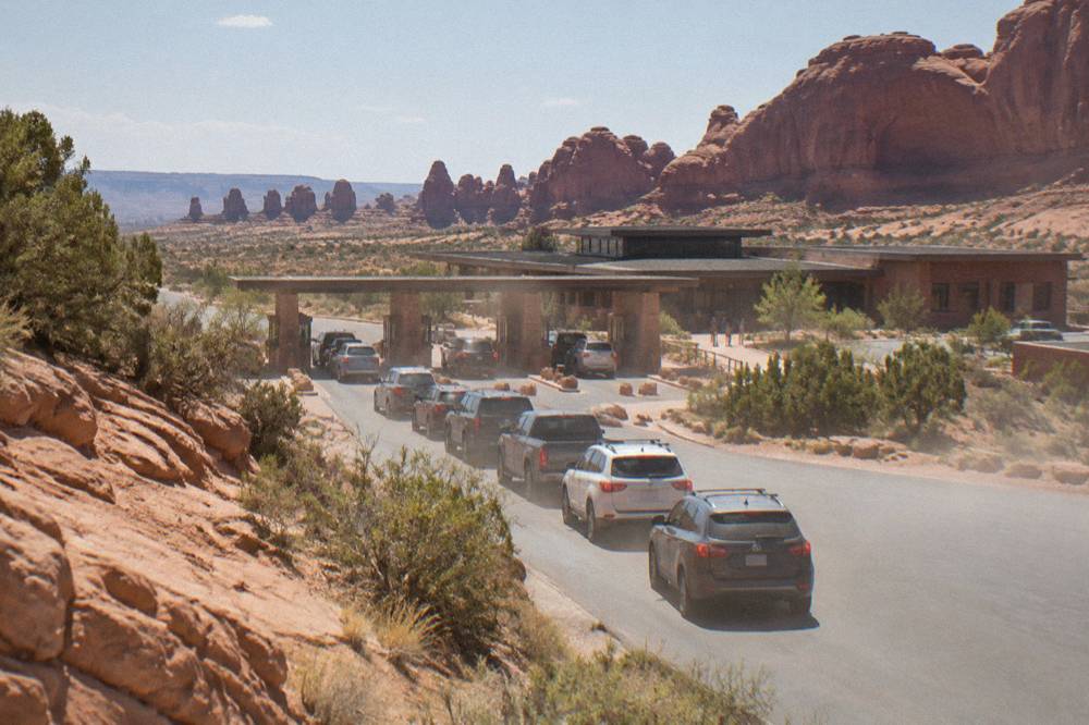 Long line of cars waiting at a park entrance station in red rock terrain