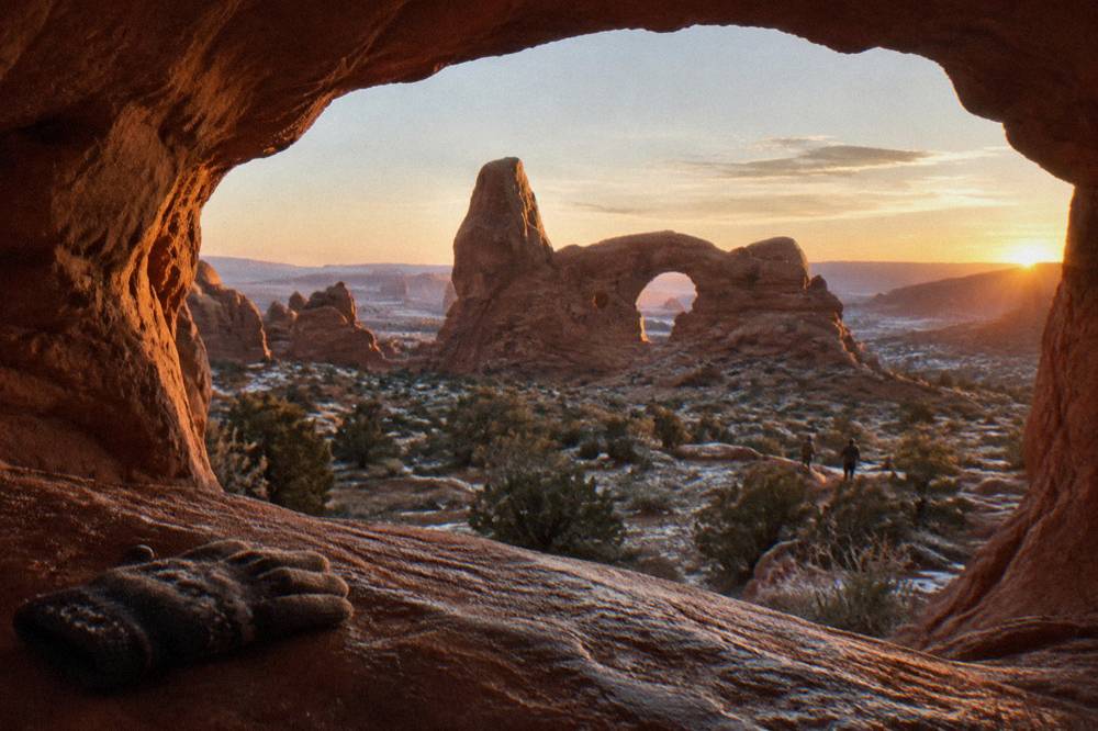 Framed view through a sandstone window opening onto another rock formation in early morning light