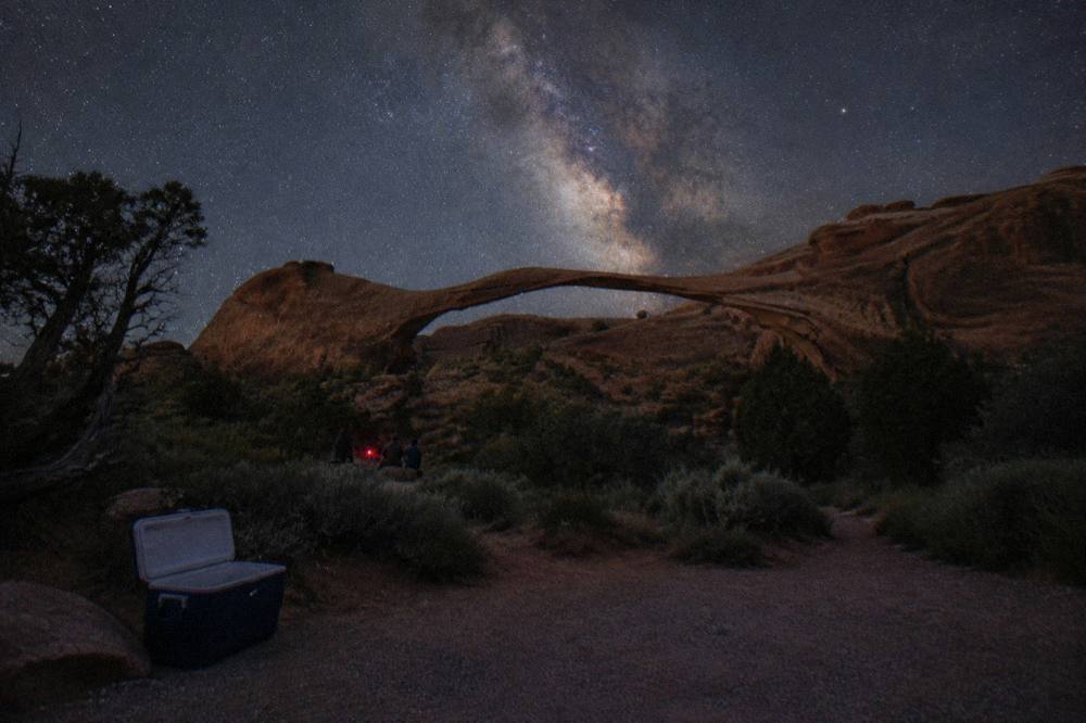 Milky Way rising over dark sandstone arch silhouettes under a star-filled sky