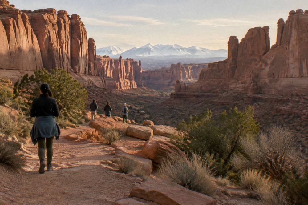 Visitors at a rocky overlook in late afternoon light with wide desert views