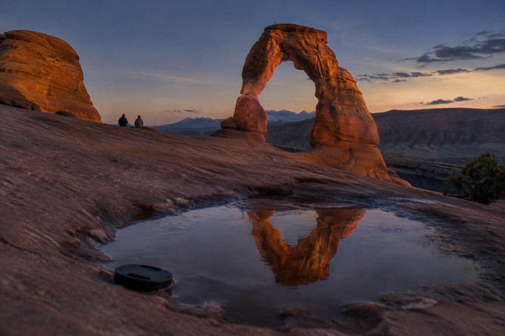 Delicate Arch glowing orange against a deepening blue evening sky at sunset