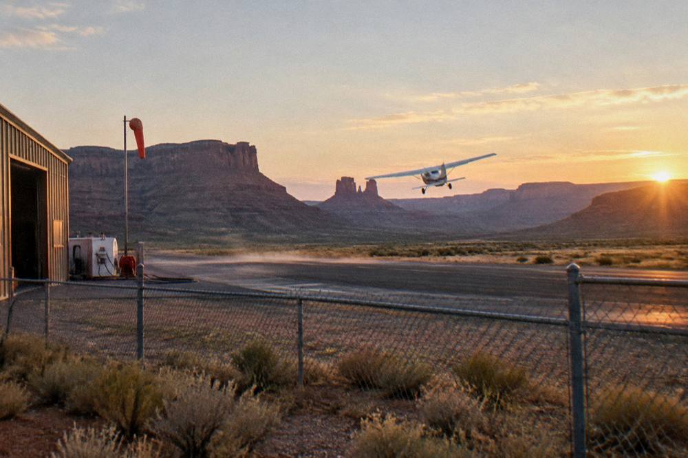 A small sightseeing airplane banking over red rock canyons and river mesas near Moab