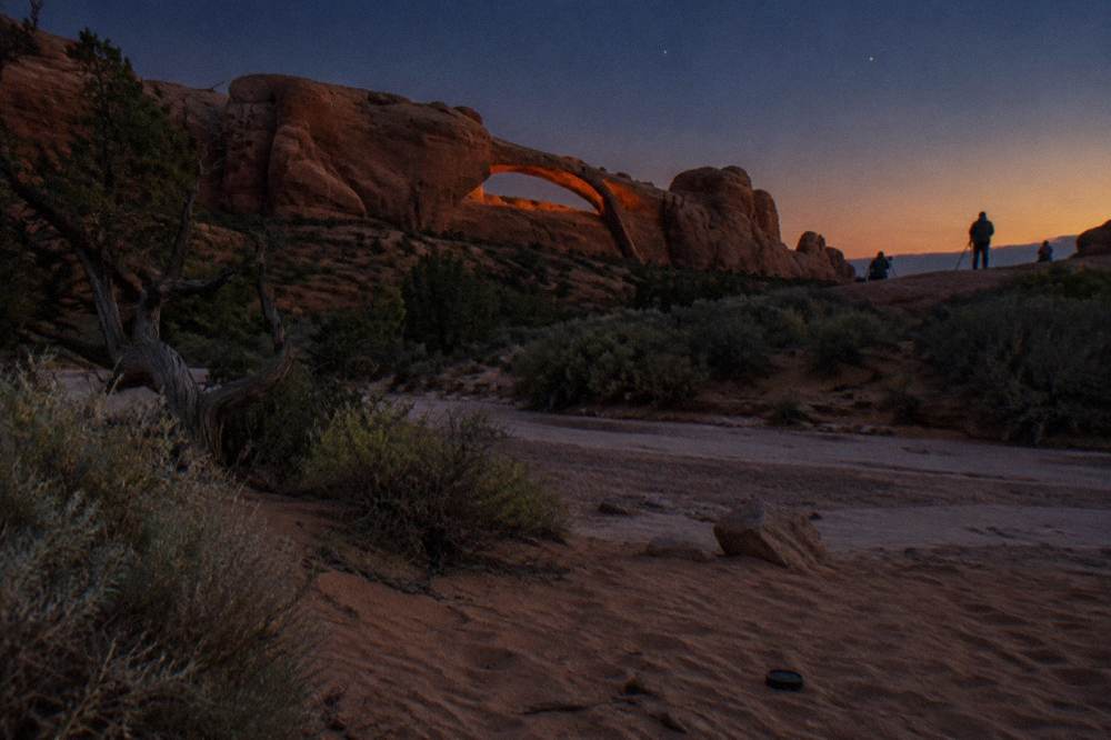 Deep orange sandstone arch glowing in late evening light under a clear sky