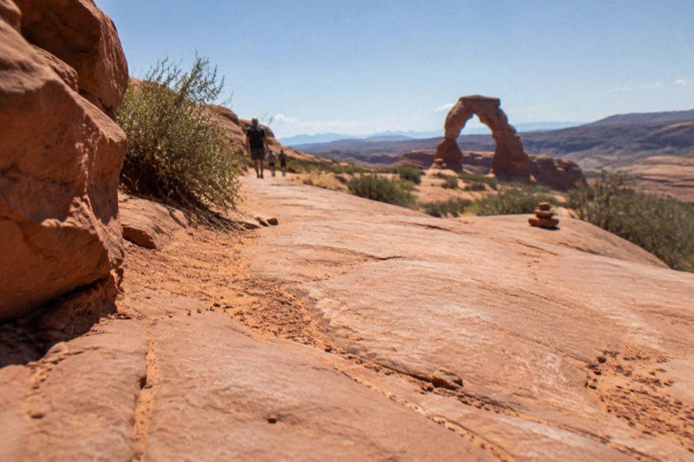 Broad expanse of open slickrock trail surface glowing orange under midday sun