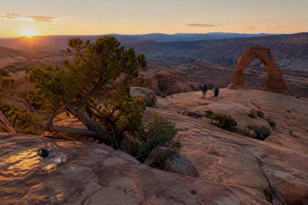 Edge of a sandstone bowl above a deep canyon at golden hour with distant ridges