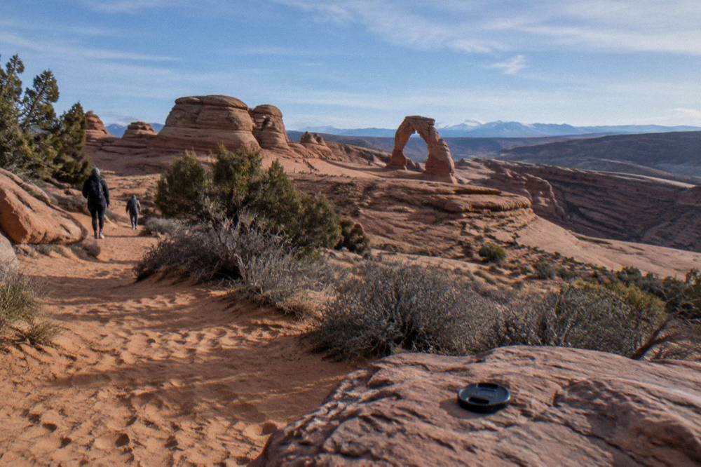 Delicate Arch seen at a distance from a sandy viewpoint path