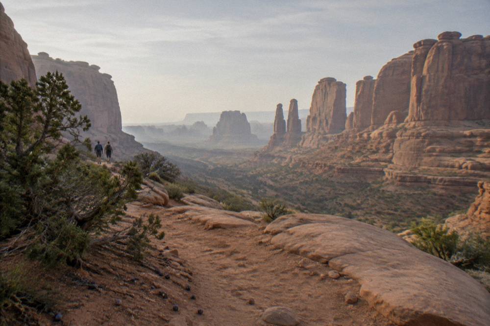 A high desert overlook with layered orange rock walls under a wide pale sky
