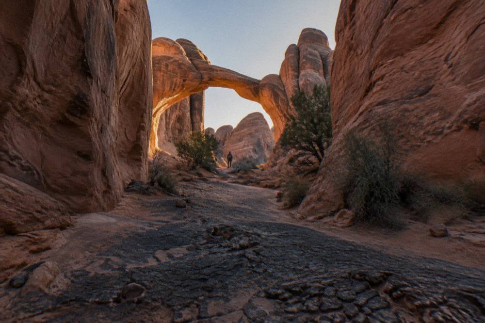 A solitary sandstone arch framed by rock fins in late afternoon light