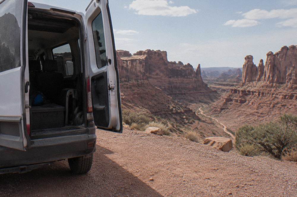 A guide's vehicle parked at a red rock overlook above winding sandstone fins