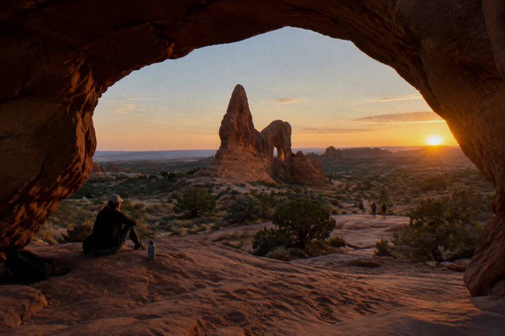Warm sunset light striking a tall freestanding arch above smooth sandstone slickrock