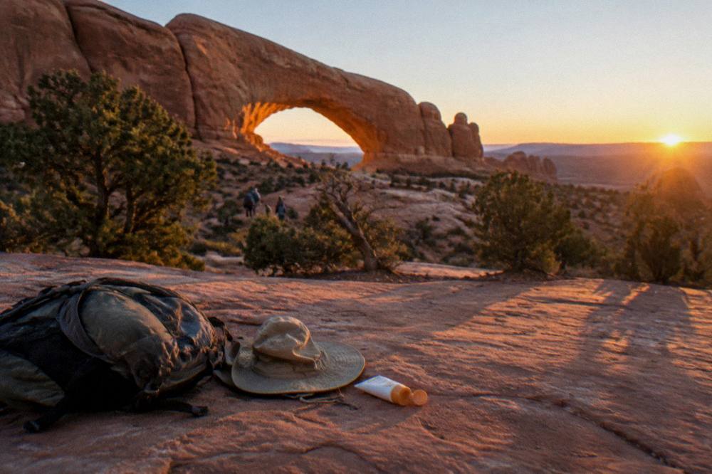 Golden sunrise light striking a large natural sandstone arch against a clear desert sky