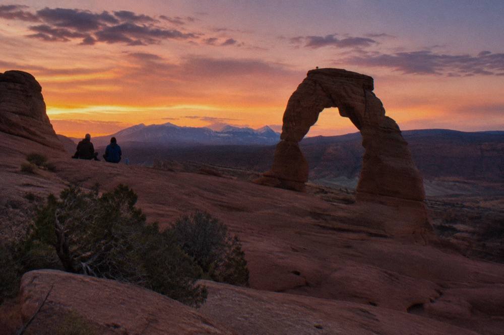 Delicate Arch framed against an orange and violet evening sky