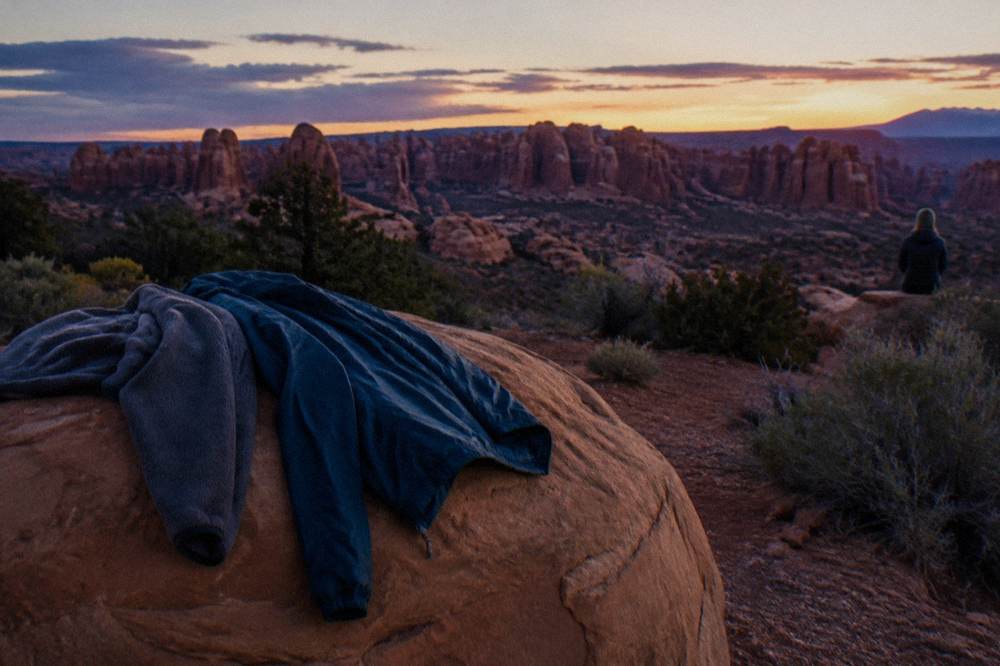 Layers draped over a rock at a desert viewpoint as evening light warms the sandstone