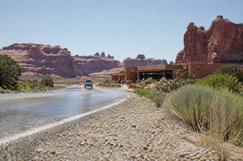 Open desert highway running north from Moab toward red rock cliffs