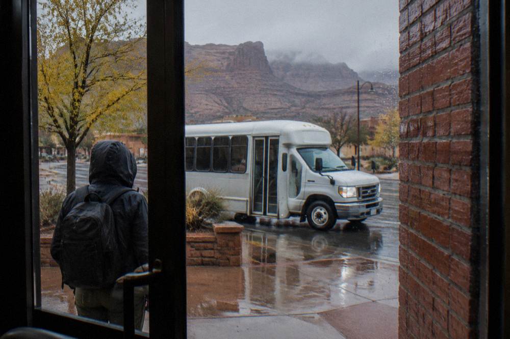 Shuttle stop sign along a Moab street with sandstone cliffs behind