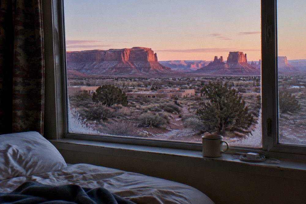 Hotel room window framing red rock buttes at sunrise in Moab
